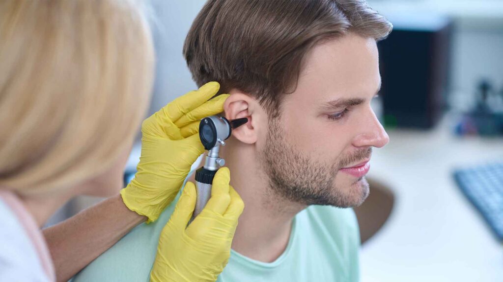 a person using an otoscope to check the ear of a man