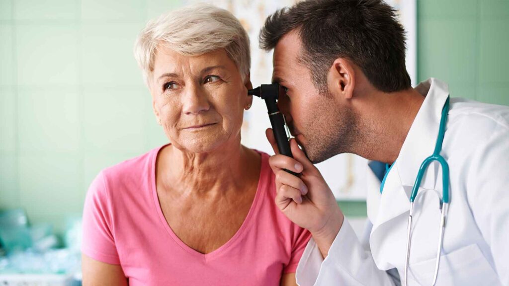 a doctor examining an old woman's ear