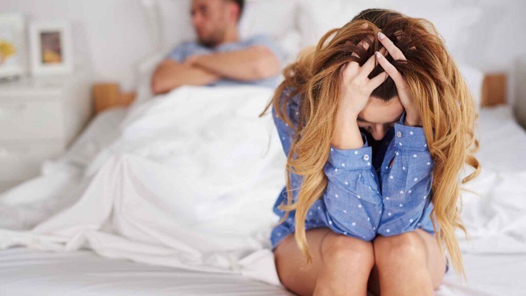 a woman sitting on a bed with her hands in her head