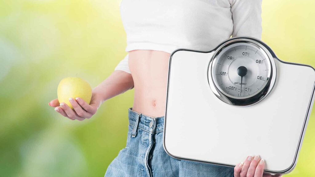 a person holding a scale and an apple