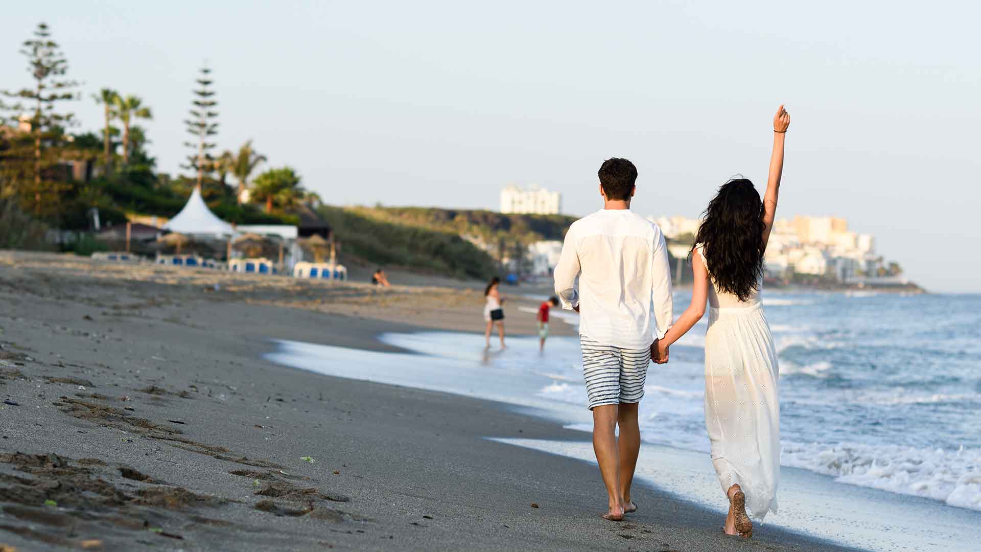 a man and woman holding hands on a beach